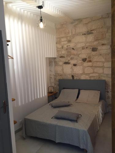une chambre avec un lit et un mur en pierre dans l'établissement Studio climatisé, La Cloison, à Arles