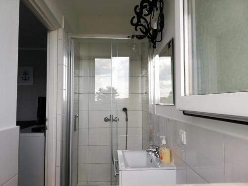 La salle de bains est pourvue d'une douche, d'un lavabo et d'un miroir. dans l'établissement Słoneczne Uroczysko, à Międzywodzie