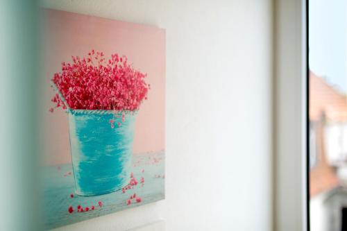 a painting of a blue vase filled with red flowers at Boardinghouse by M&K in Bad Oeynhausen