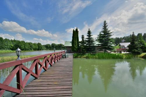 a bridge over a river with a person sitting on a bench at Domek nad stawem in Działdowo