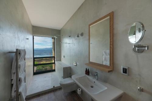 a bathroom with a sink and a toilet and a window at Alkira Lodge in Brenton-on-Sea