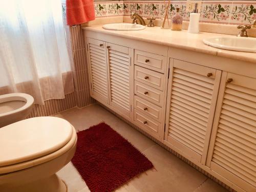 La salle de bains est pourvue de toilettes blanches, d'un lavabo et de toilettes. dans l'établissement Lo del Colo, à Canning