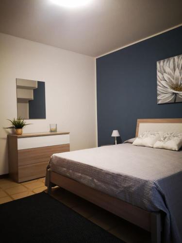 a bedroom with a bed and a blue wall at Nino's Apartments in Giardini Naxos