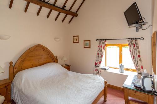 a bedroom with a bed and a tv on the wall at Church Farm Lodge in Harrington