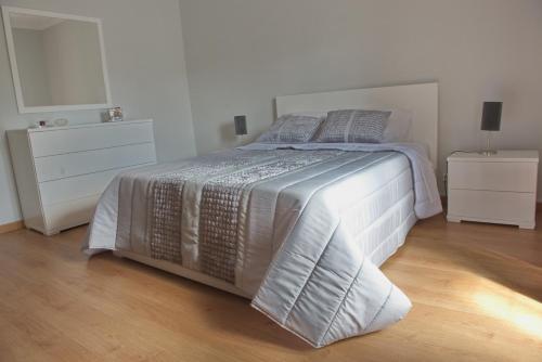 a bedroom with a white bed with two dressers at Just Like Home in Ponta Delgada