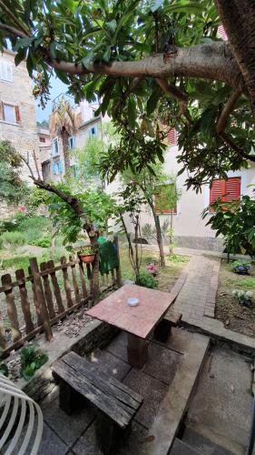 a picnic table under a tree next to a fence at Apartmaji Mila Piran in Piran