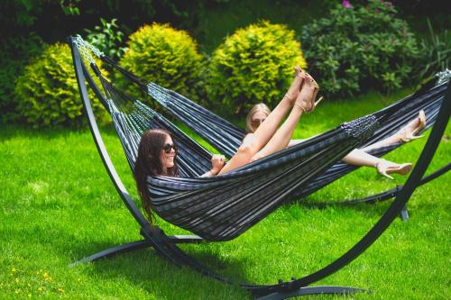 two women laying in a hammock on the grass at Kolumna Park Hotel in Dobroń
