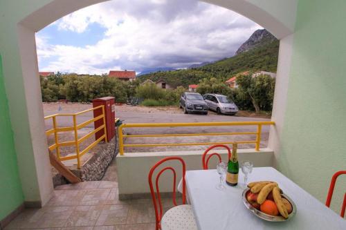 a table with a bowl of fruit on a balcony at Apartments Natalika in Podaca