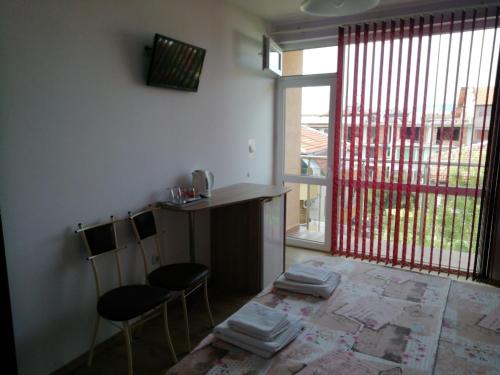 a kitchen with two chairs and a table and a window at Guest House Nedelchevi in Primorsko