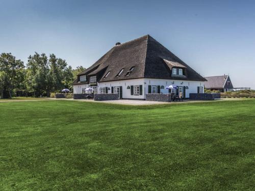 une maison blanche avec un toit noir sur un champ vert dans l'établissement Comfortable flat in De Cocksdorp near sea, à De Cocksdorp