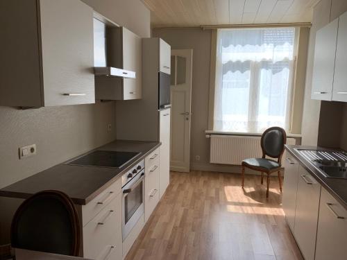 uma cozinha com armários brancos e uma mesa e cadeiras em Vakantiehuis Babelle 2 em Blankenberge