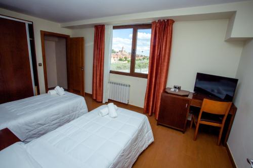 a hotel room with two beds and a desk and a television at Hotel Villa De Cárcar in Cárcar