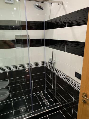 ドゥラスにあるEKA Luxury Two-Bedroom Premium Penthouseの黒と白のタイル張りのバスルーム(シャワー付)