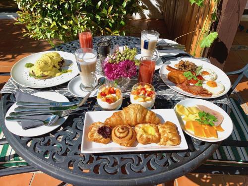 a table with plates of breakfast foods on it at Vine Guesthouse in Stellenbosch