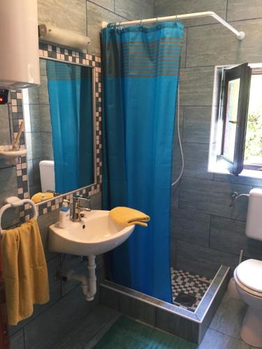 a bathroom with a sink and a blue shower curtain at Lovely studio apartment Mare e Sole in Labin