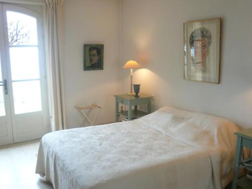 a white bedroom with a bed and a window at Sunny holiday home in Provence with pool in Séguret