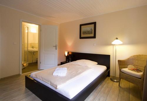 1 dormitorio con cama, lámpara y silla en Heidehotel Gut Landliebe Restaurant Montags Ruhetag!, en Hermannsburg