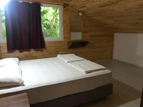 a bed in a wooden room with a window at Yildiz Pension Bungalows in Cıralı