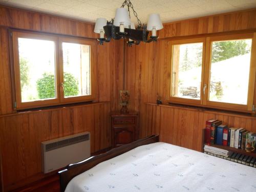 a bedroom with wooden walls and a bed and windows at PRA BIQUET in Les Thuiles