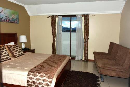 a bedroom with a bed and a chair and a window at Alejandrina Hotel in Cuenca