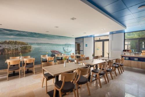 a restaurant with tables and chairs and a mural at Hotel Solero in Siófok