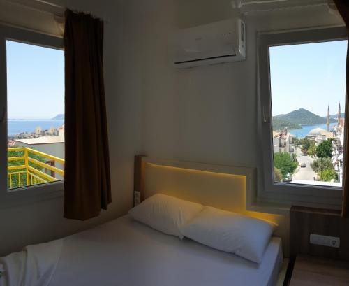 1 dormitorio con 1 cama y 2 ventanas grandes en Limon Pansiyon, en Kas