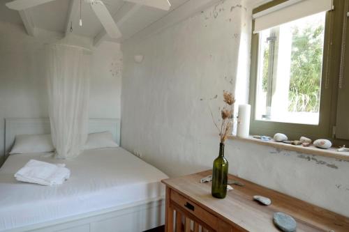 1 dormitorio con cama, ventana y jarrón sobre una mesa en BUFO - Serifians, en Serifos Chora