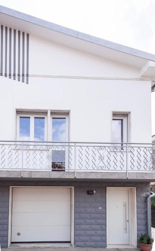 a white house with two garage doors and a balcony at Cà Fernanda in Fiesso Umbertiano