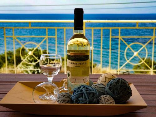a bottle of wine and a glass on a table at Derveni Seaside Apartments - Deluxe Sea View Penthouse Jacuzzi-BBQ & Groundfloor Garden View Apartment in Derveni