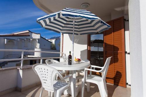 a table and chairs on a balcony with an umbrella at Apartman Vjekoslav in Krk