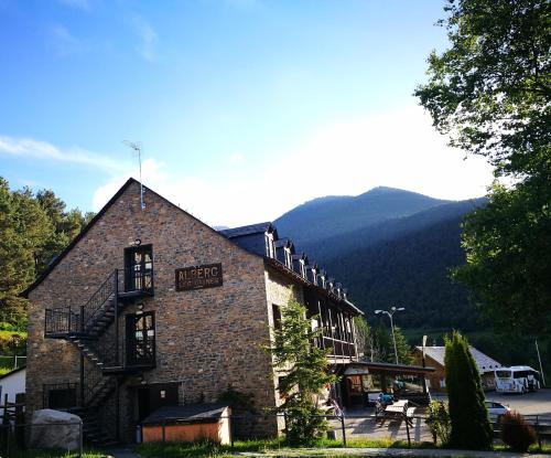 a large brick building with mountains in the background at Alberg Les Daines in Espot