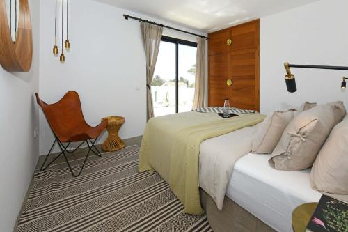 a bedroom with a bed and a chair and a window at Villa Casajable in Pájara