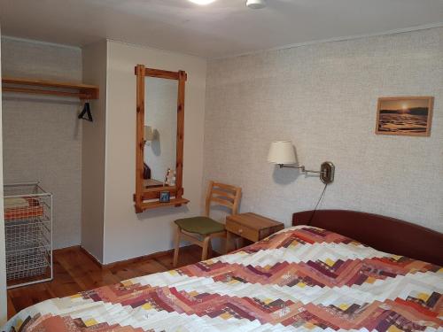a bedroom with a bed and a chair and a mirror at Nõva Madise Guesthouse in Rannaküla
