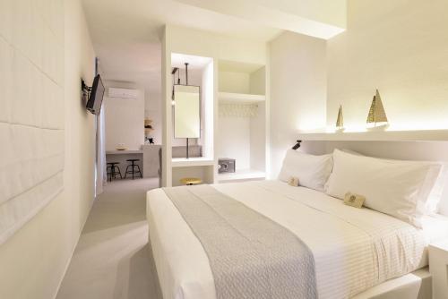 a white bedroom with a large white bed with white pillows at Peven Suites in Naousa