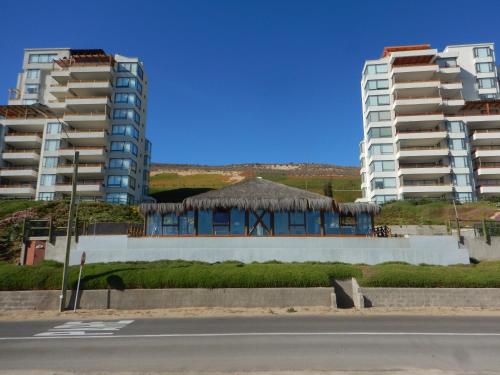 a building with a straw roof and two tall buildings at Departamento Puerto Velero in Puerto Velero