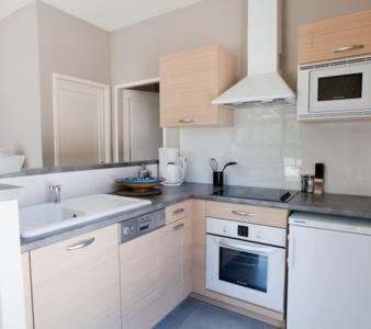 une cuisine blanche avec un évier et une cuisinière dans l'établissement Gites la Filature, à Laudun-l'Ardoise