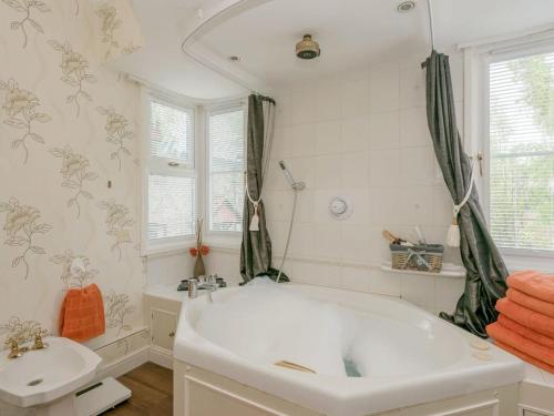 a white bathroom with a tub and a sink at Villa Morea - 5 Bed in Horning