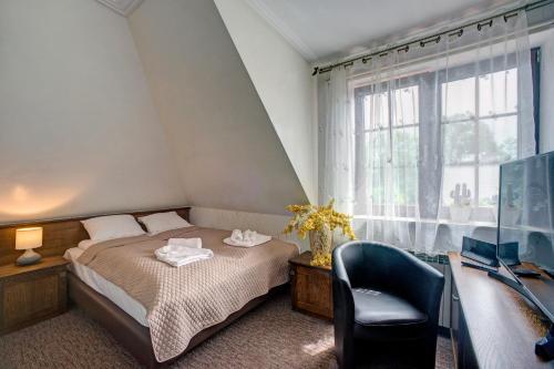 - une chambre avec un lit, une chaise et une télévision dans l'établissement Pokoje Gościnne Murowanka, à Przemyśl