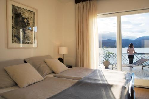 a living room with a couch and a woman looking out the window at Hotel Linde in Maria Wörth