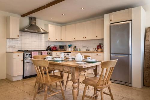 a kitchen with a wooden table with chairs and a refrigerator at Cottage 1 New Yatt Farm in Wilcote