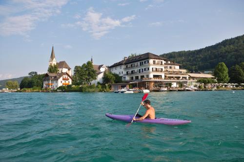 a man in a purple kayak in the water at Hotel Linde in Maria Wörth