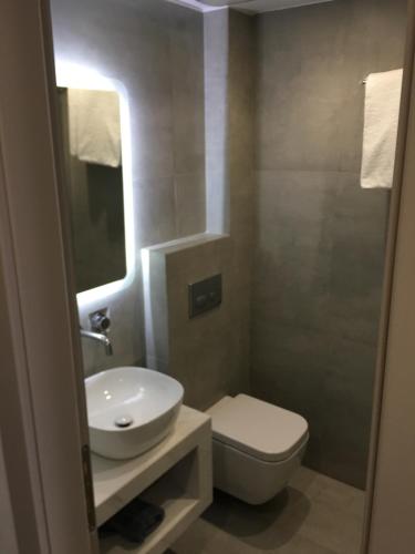 a bathroom with a white sink and a toilet at Olympos Suites Apartments in Leptokaria