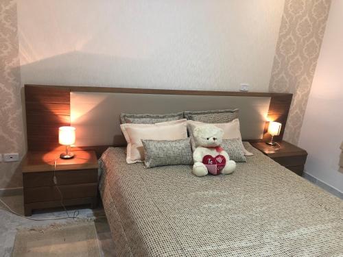 a teddy bear sitting on a bed with two lamps at Apartment Jardin Carthage in Tunis