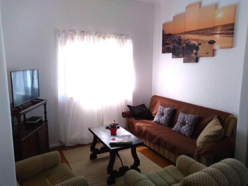 a living room with a couch and a table and a television at Beach house with garden in Sintra