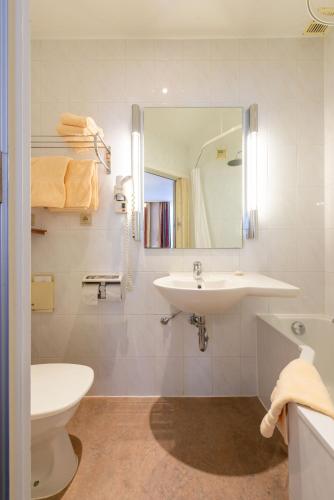 a bathroom with a sink and a toilet and a mirror at The Black Swan Hotel in Bruges