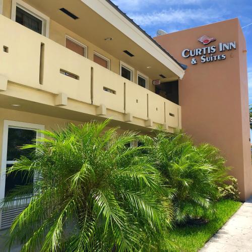 a building with a palm tree in front of it at Curtis Inn & Suites in Hollywood