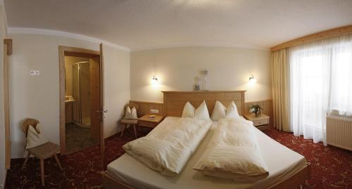 a hotel room with a bed with white pillows at Landhaus Tirol in Zellberg