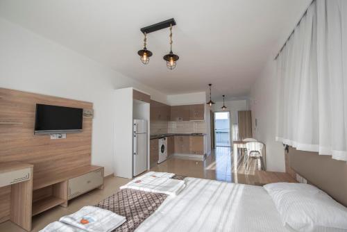 a bedroom with a white bed and a kitchen at Deniz Airport Suites in North Nicosia