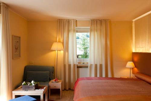 1 dormitorio con 1 cama, 1 silla y 1 ventana en Maratscher Kunst & Kulturhotel, en Lagundo