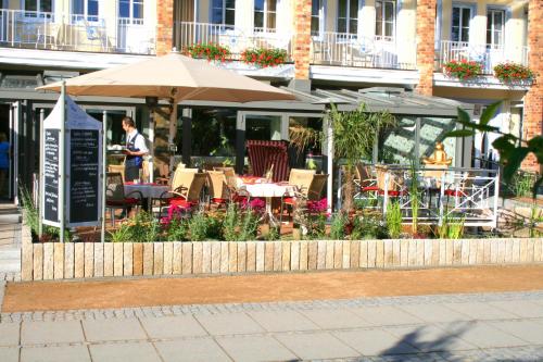 a restaurant with tables and chairs and an umbrella at Vineta Strandhotels in Zinnowitz